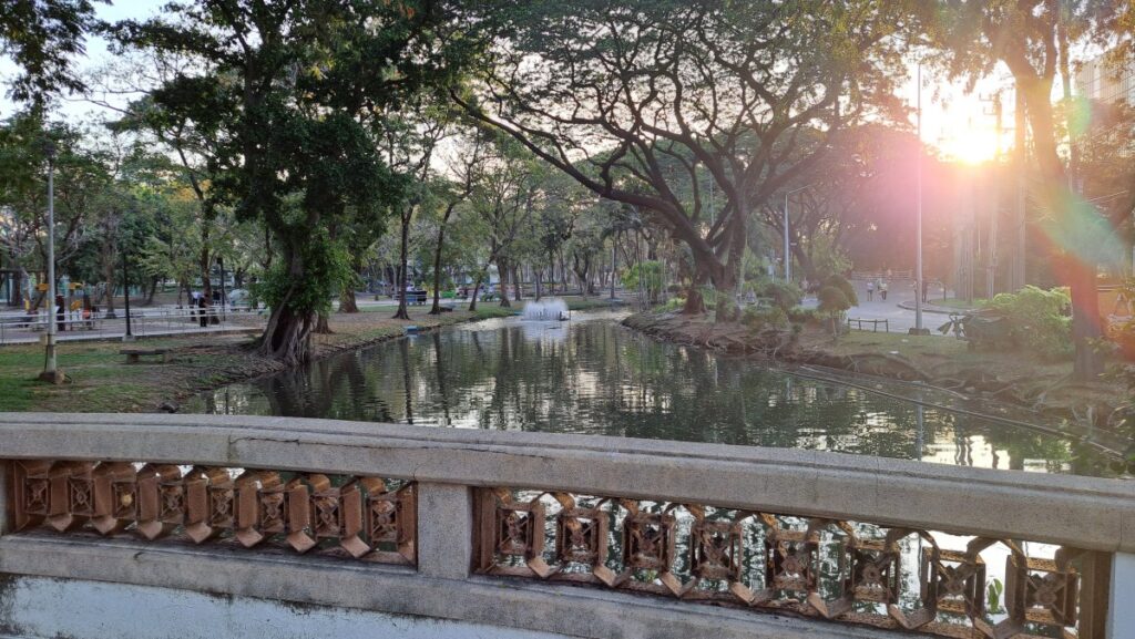 ルンビニー公園の情景。橋と木々、差し込む朝日が美しい。