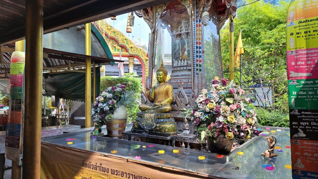 花に囲まれた金色の仏像が静かに佇む。